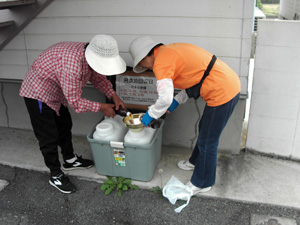 住民が回収ボックスに廃食用油を移し替えている様子