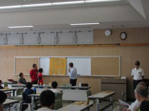 ホワイトボードに設置した解説用の将棋盤を見ながら将棋をする講師と生徒