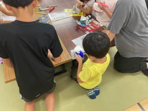 牛乳パックに色を塗りパクパク人形を作成する小学生の様子