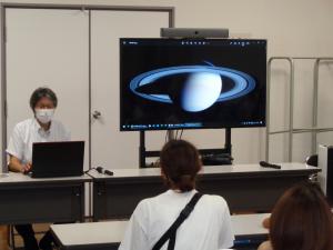 講師が土星の輪っかについてモニターの映像を使って説明している様子