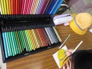 何色もある色鉛筆をの中から色んな色を使って黄帽を描いている写真