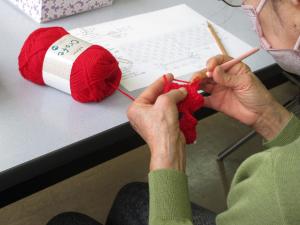 赤い毛糸でいちごのポーチを編む受講生の様子
