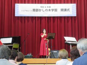 舞台の上でマイクを持って歌っている演者