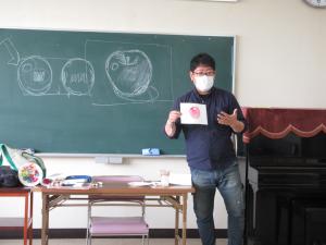 りんごの色付けを黒板を使って説明している講師の写真