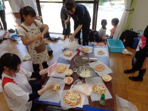 ピザ生地に具材を乗せる子供の様子