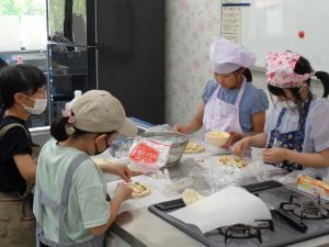 ピザ生地に丁寧に具材をのせる子供たち