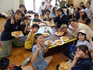 黄色班：嬉しそうに出来上がったピザの前でポーズをとる子供たち