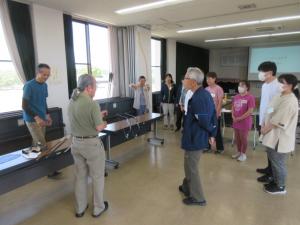 弓の道具を説明している講師と話を聞いている受講生