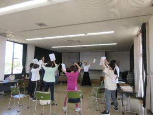 輪になって弓を引く形をする練習で、両手を上げている受講生