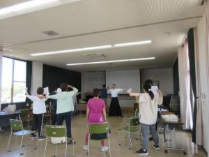 輪になって弓を引く形をする練習で、狙いを定めている受講生