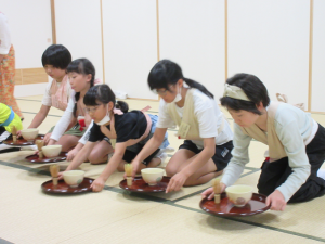 茶碗と茶せんを受け取る子供たち