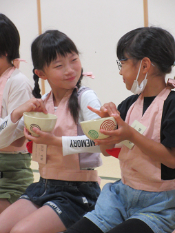 茶碗の飲み口を右手親指と人差し指で拭う子供たち