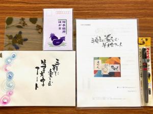 机に並べられたテキストとはがき、筆ペン