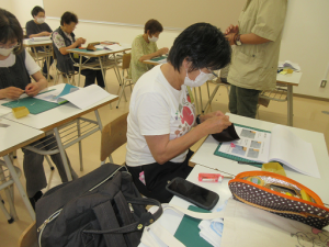 黒い皮の小銭入れを縫っている受講生