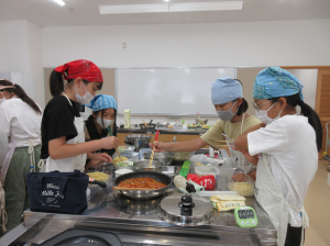 子供たち４人がフライパンの材料を混ぜている写真