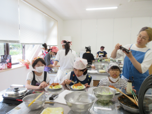完成した料理をお皿に盛り付ける子供とその様子を撮影する講師