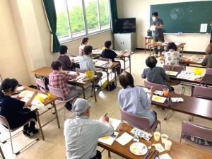 見本を手に着色の説明をする講師の写真