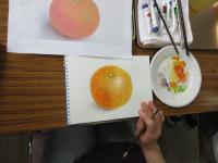 パレットや絵の具、筆とミカンの絵の写真