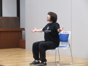 椅子に座って両手を横に広げてお話しされる深澤先生