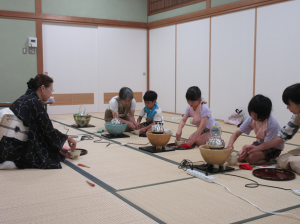 お茶碗のお抹茶を茶せんでたてる子ども達