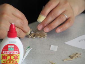 クラフトバンドで花のブローチを作っている手元の様子