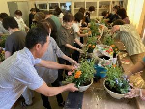 生徒の寄せ植えを手直ししている講師の写真