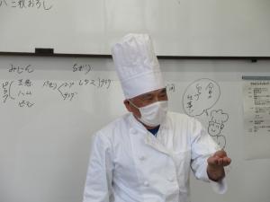 高さのあるコック帽をかぶり、自己紹介をする講師の様子