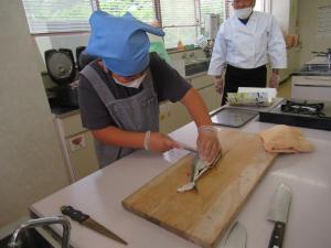 魚を左手で押さえて、魚の背中をさばいている様子