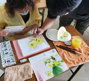 画材の花の色付けを指導をされる先生の様子