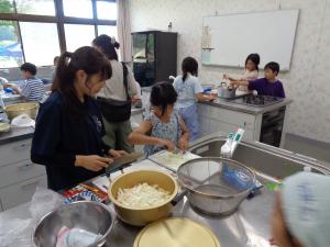 カレー班の女の子が大学生スタッフと具材切りに挑戦する様子