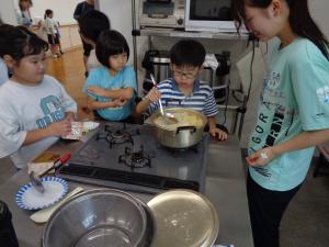 具材の煮え具合を確認する子とそれを見守るスタッフと班員