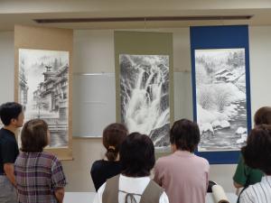 出展の３幅の掛軸を鑑賞する受講生。左から「朝もらに包まれる温泉街の風景」「飛泉という題の滝の絵」「雪景色の山間の一軒家の絵」