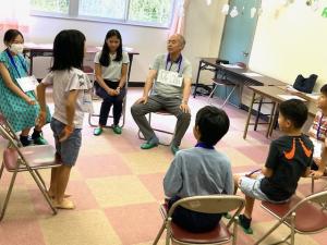 輪になったゲームで質問をする子供の写真