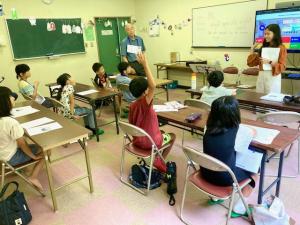 クイズに答えるために手を挙げている子供の写真