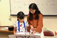 発音の仕方を教えてもらいながら発表をする子供の写真