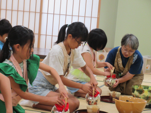 鉄瓶からお湯を注ぐ子ども達