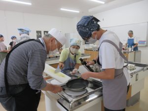 フライパンにオリーブオイルを入れ材料を炒める男性グループの皆さん