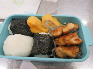 おにぎりと卵焼き、鶏もも肉が入れられたお弁当。野菜が足りないのでは？