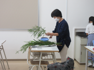 メラリューカを手に取り見本を生けられる講師先生