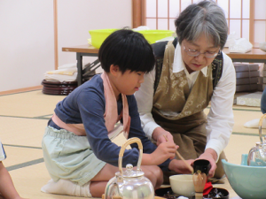 年度途中から入級した児童に茶杓でお抹茶を入れる方法を優しく教える志方先生