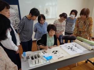 自宅で描いた絵の指導を受ける生徒さん、それを周りで見学する生徒さん