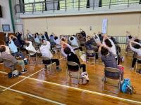 座ったまま体を伸ばすストレッチをする様子