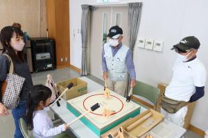 土俵の上に紙で作った力士を置き、太鼓のバチで土俵を叩いて倒す「たいこ相撲」ゲームの様子