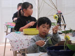黄色のガーベラにはさみを入れる受講生の子ども