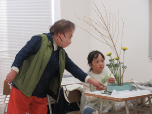 出来上がった生け花を前にするこどもに声かけをされる講師先生