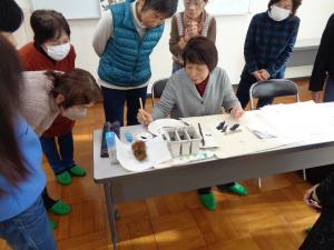 実際のイガを見本に手本を描く講師先生とそれを見入る生徒さんたち