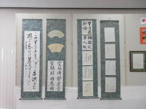 条幅作品、扇に書かれた作品などグループの皆さんの作品が展示されている様子
