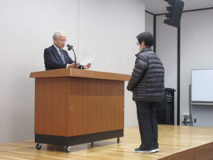 壇上で皆勤賞を読みあげる館長と受講生