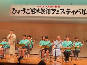 お揃いのペパーミントグリーンのＴシャツ舞台で三味線を演奏する子供たちの様子