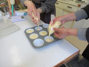ナイロン袋に入れた生地をマフィン型に入れる様子